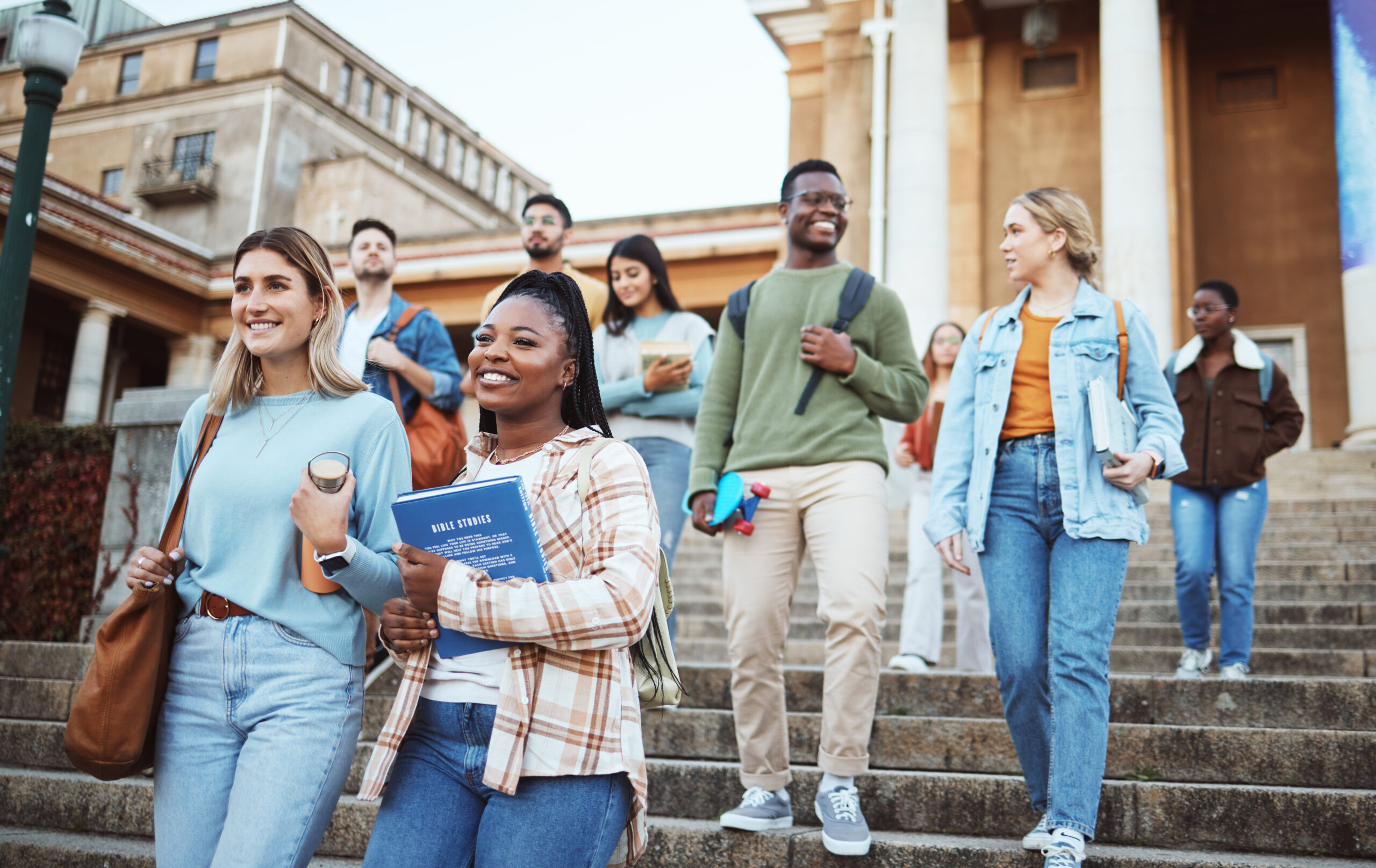 Diversity, students and walking on university steps, school stairs or college campus to morning class. Smile, happy people and bonding education friends in global scholarship opportunity or open day.