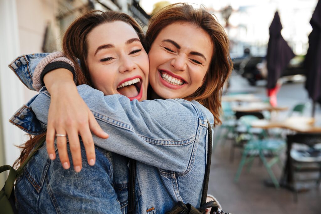 Close-up photo of laughing woman friends hugging each other